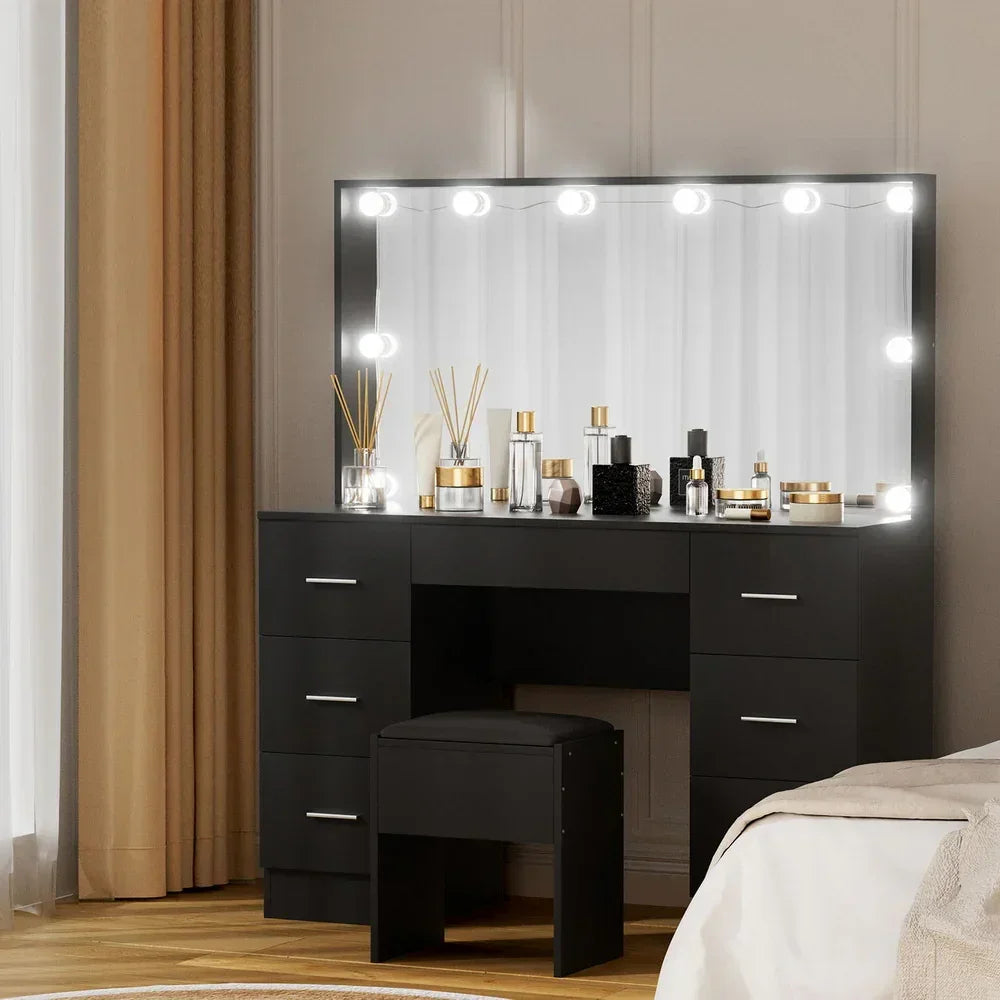 Black vanity table with LED mirror, storage drawers, stool, and assorted cosmetic bottles