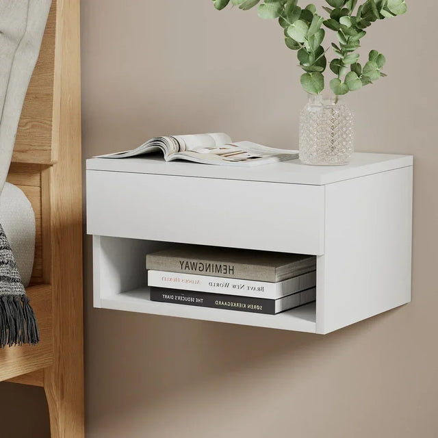 Modern white floating bedside table with shelf, glass vase and books, wall-mounted design