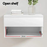 White floating wall shelf with open compartment, labeled dimensions 37cm x 28cm x 9.5cm, books and plant decor on top.