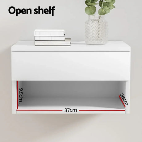 White floating wall shelf with open compartment, labeled dimensions 37cm x 28cm x 9.5cm, books and plant decor on top.