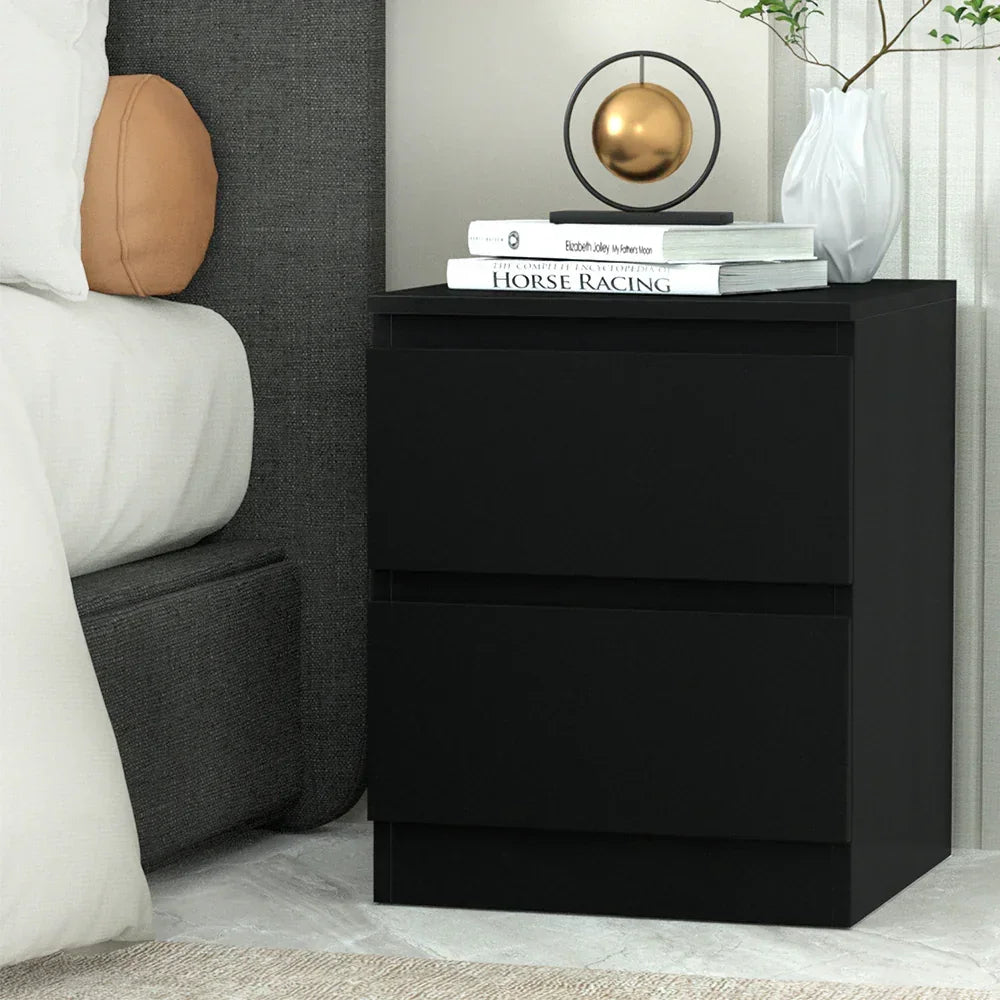 Modern black bedside table with two drawers, lamp, books, and white vase in bedroom