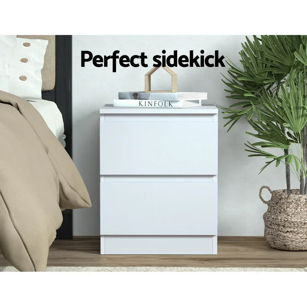 Modern white bedside table with drawers, styled with books and decor in a cozy bedroom