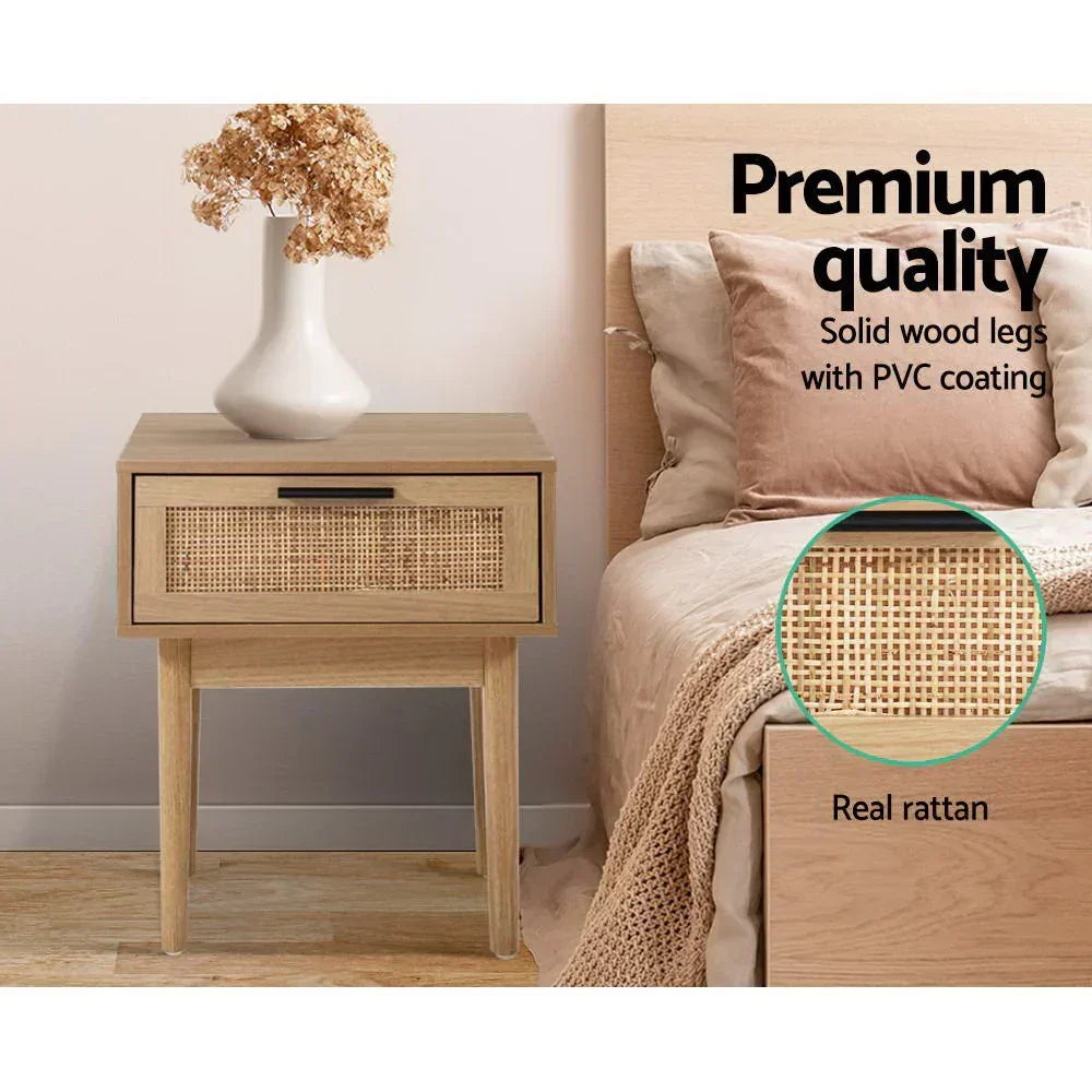 Wooden bedside table with rattan drawer, solid wood legs, next to bed in modern bedroom.
