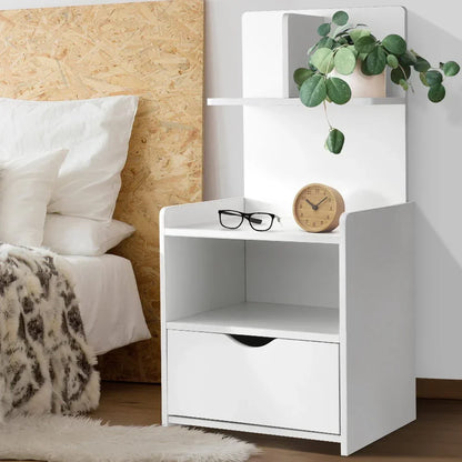 Modern white bedside table with drawer, shelf, clock, glasses, and potted plant in a bedroom