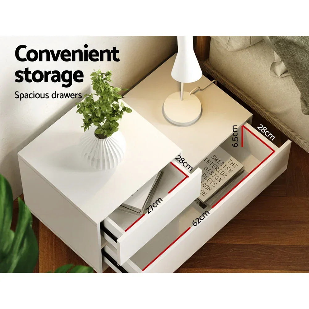 White bedside table with two spacious drawers, lamp, plant and drawer dimensions shown.