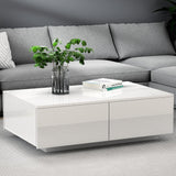 Modern white gloss coffee table in living room with grey sofa, books, and plant decor