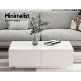 White minimalist coffee table with storage drawers in front of a light grey sofa, modern decor