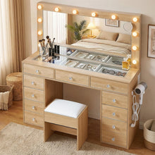 Wooden makeup vanity table with lighted mirror, drawers, and cushioned stool in bedroom.
