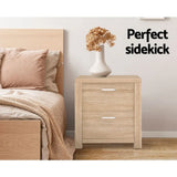 Light wood bedside table with two drawers, ceramic vase, and dried flowers in modern bedroom