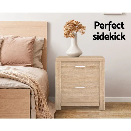 Light wood bedside table with two drawers, ceramic vase, and dried flowers in modern bedroom