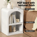 White MDF board bedside table with textured finish, books, and decor items in a modern bedroom.