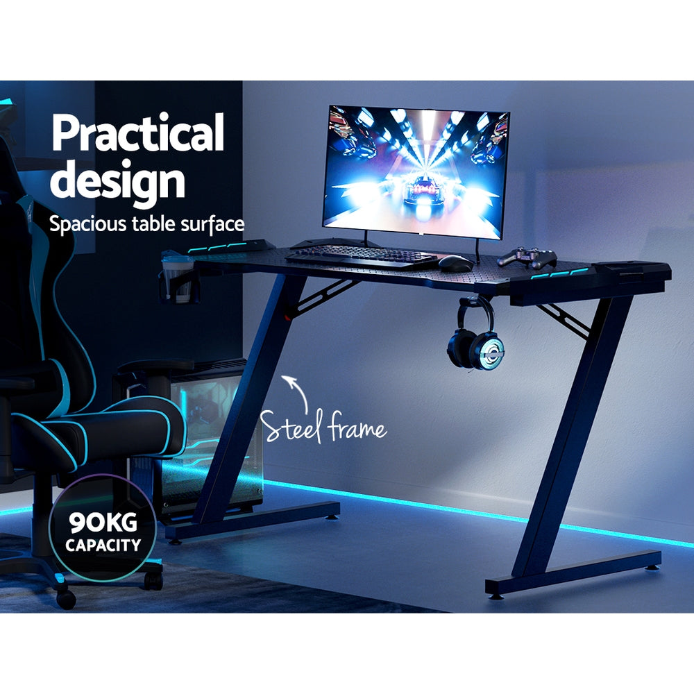 Gaming desk with steel frame, LED lighting, 90kg capacity, spacious surface for monitor, keyboard, and accessories