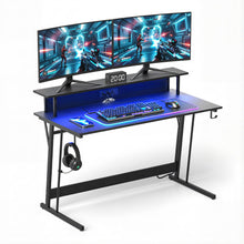 Gaming desk with dual monitors, RGB keyboard, mouse, and headset, featuring blue LED lighting and monitor stand.