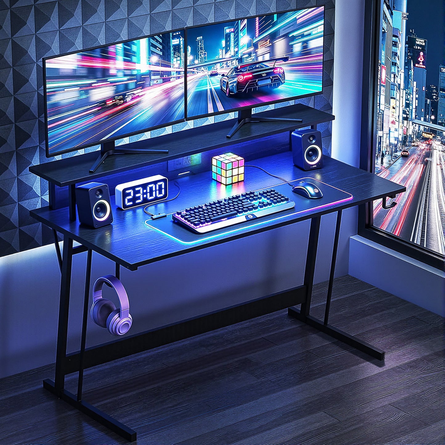 Gaming desk setup with dual monitors, RGB keyboard, speakers, and neon city view