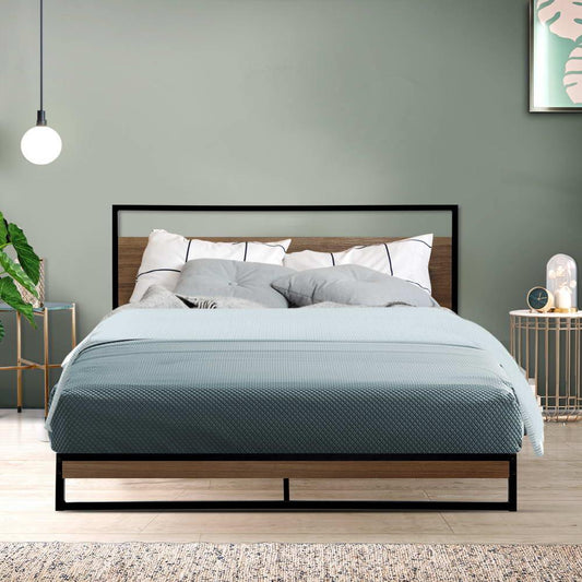 Modern bedroom with queen bed featuring black metal frame, wood headboard, blue quilt, and patterned pillows
