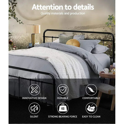 Black metal frame bed with gray bedding, white knitted blanket, assorted pillows, bedside lamp, and wooden side table