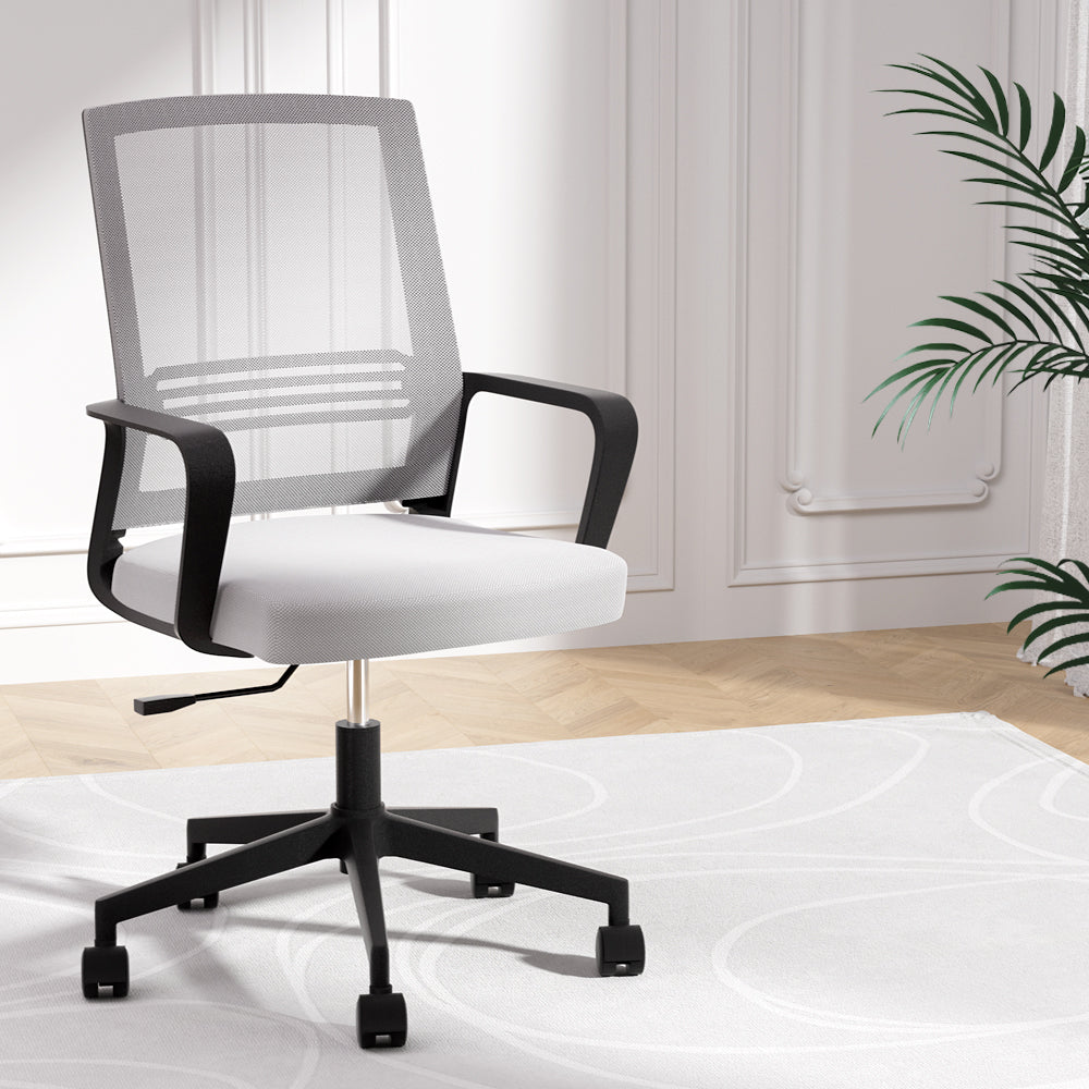Modern mesh office chair with white cushion, black frame, and rolling casters in a bright room