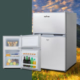 White Glacio mini fridge with open doors showing drinks, eggs, and fresh produce inside, set against scenic outdoor backdrop
