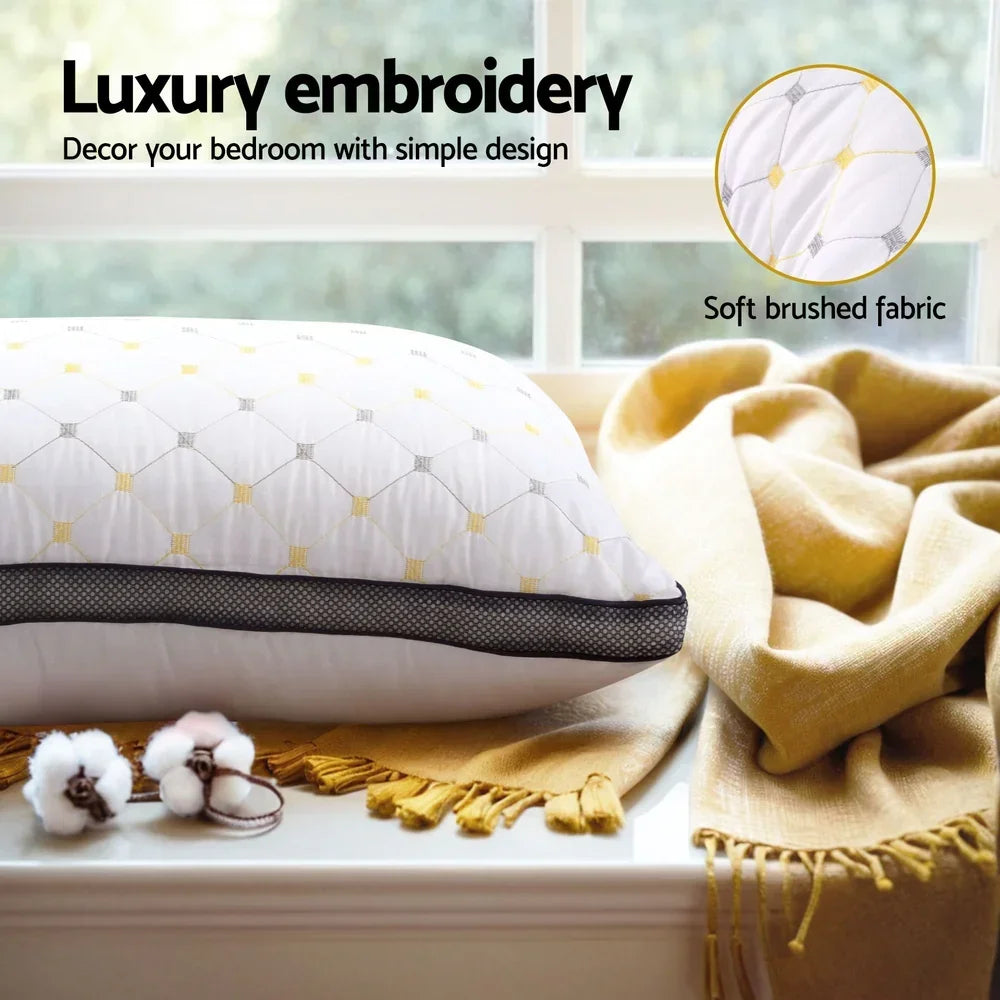 White luxury embroidered pillow with yellow accents on window sill next to soft brushed mustard yellow blanket