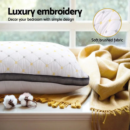 Luxury embroidered white pillow with soft brushed fabric on a windowsill with yellow blanket and cotton branches