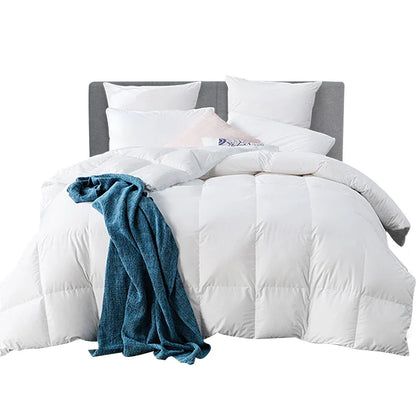 White quilted comforter on bed with pillows and blue throw blanket