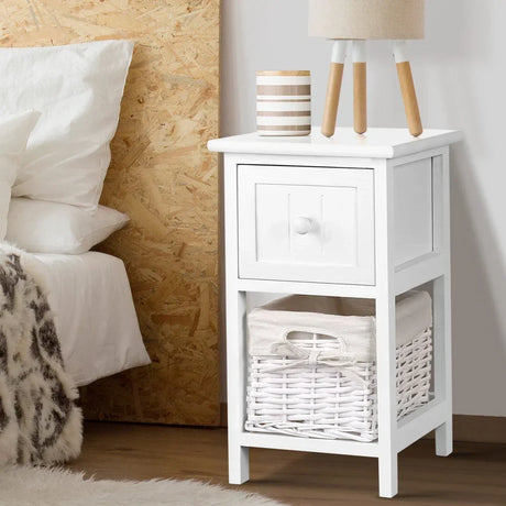 White wooden nightstand with drawer and wicker basket, lamp and decor in cozy bedroom
