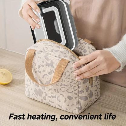 Person placing a black electric lunch box into a beige leopard print insulated bag on a kitchen counter.