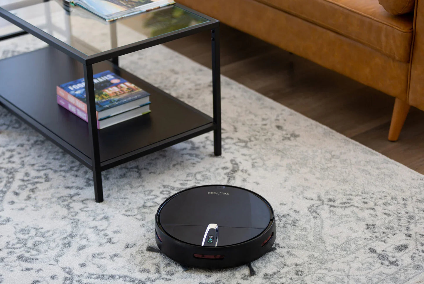 Robot vacuum cleaner on patterned rug in modern living room with coffee table and sofa