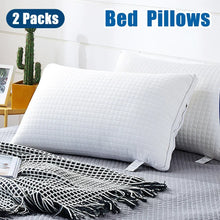 Two-pack white quilted bed pillows on a grey bed with black and white checkered throw blanket
