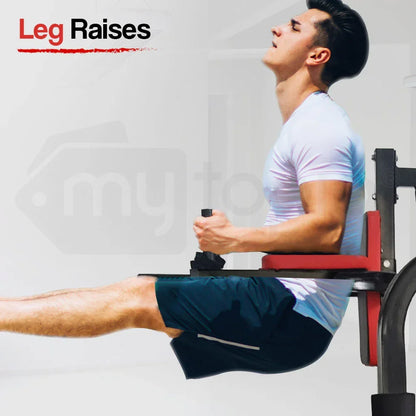 Man in gym performing leg raises on captain's chair, wearing white shirt and blue shorts