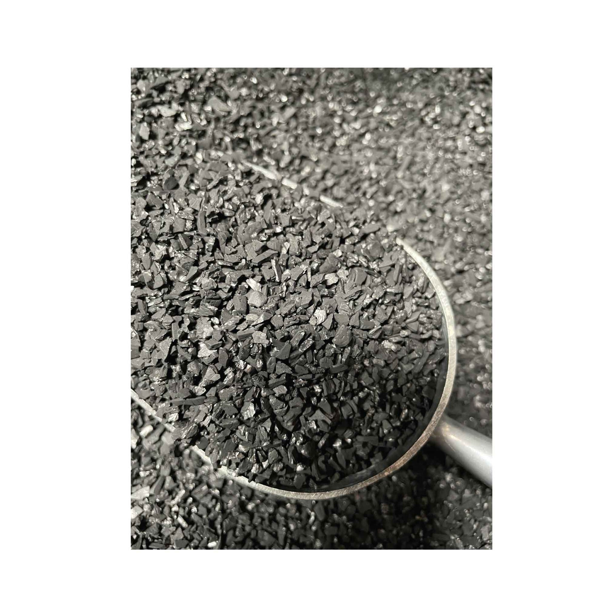 Black granular charcoal in a metal scoop, ideal for grilling and outdoor cooking