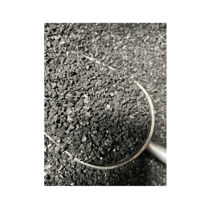 Black granular charcoal in a metal scoop, ideal for grilling and outdoor cooking