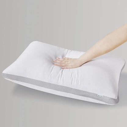 Hand pressing soft white memory foam pillow with breathable mesh sides on gray background