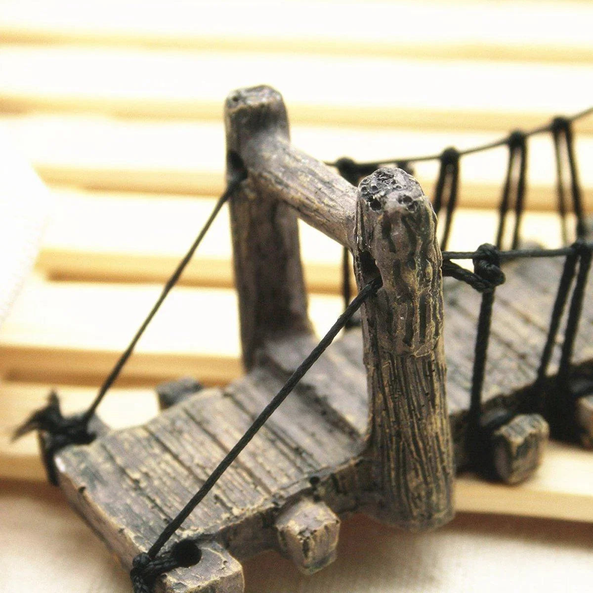 Miniature rustic wooden suspension bridge with black rope, decorative garden accessory
