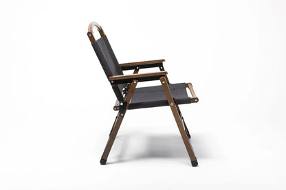 Side view of a black fabric and wooden outdoor folding chair with armrests on white background