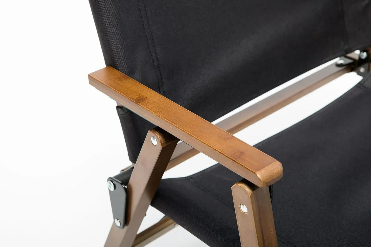 Close-up of black fabric chair with wooden armrest and metal support on white background