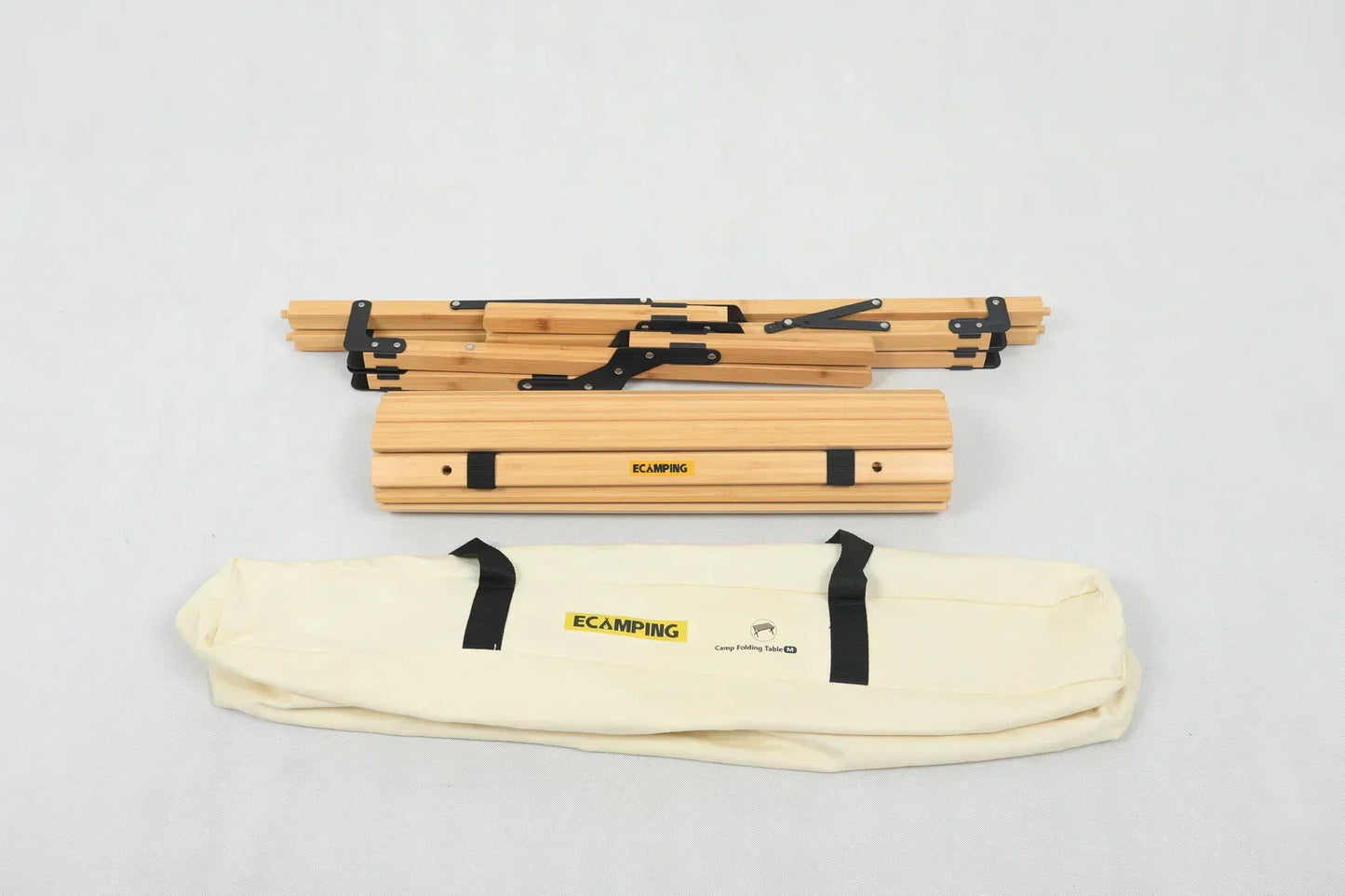 Folded wooden camping table with black metal hinges and cream carrying bag labeled ECAMPING