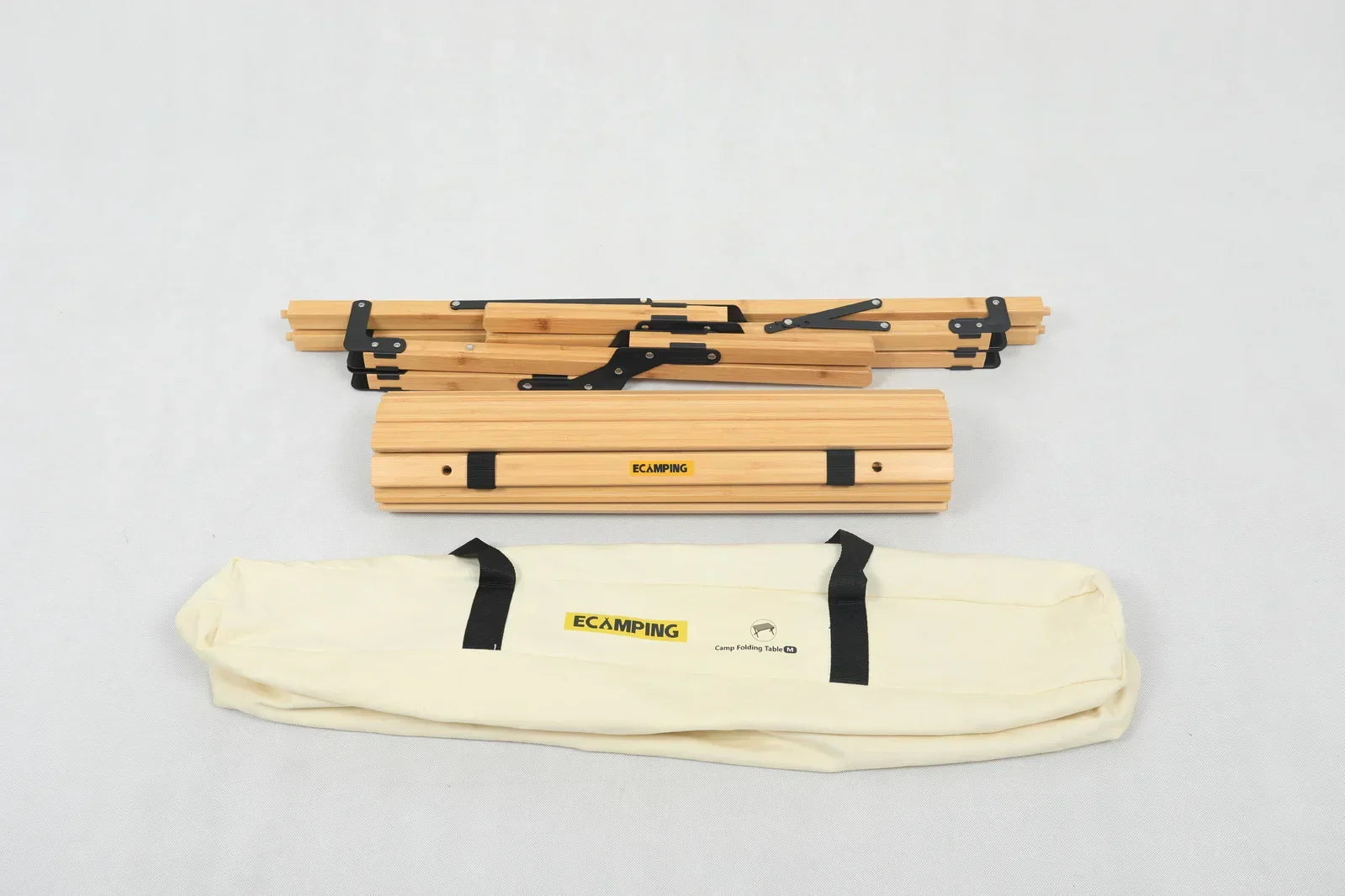 Folded wooden camping table with black metal hinges and cream carrying bag labeled ECAMPING