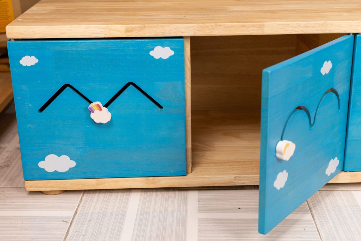 Blue kids storage cabinet with cloud and rainbow design, wooden top, open door revealing shelf