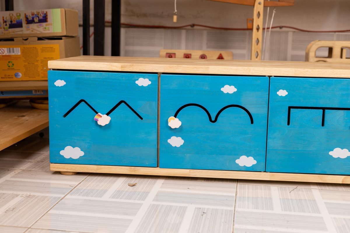 Blue kids storage unit with cloud and mountain designs, wooden top, playful nursery organizer