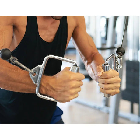 Muscular man in black tank top performing cable chest fly exercise in gym