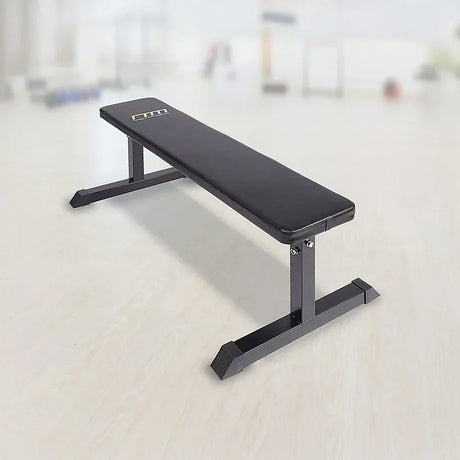 Flat weight bench with black padded seat in a bright gym setting