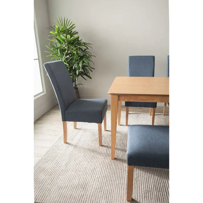 Modern dining room with light wood table, blue upholstered chairs, indoor plant, and rug