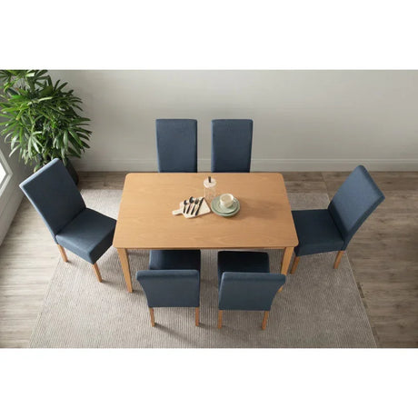 Modern dining room with light wood table, six blue chairs, dishes, and plant on rug