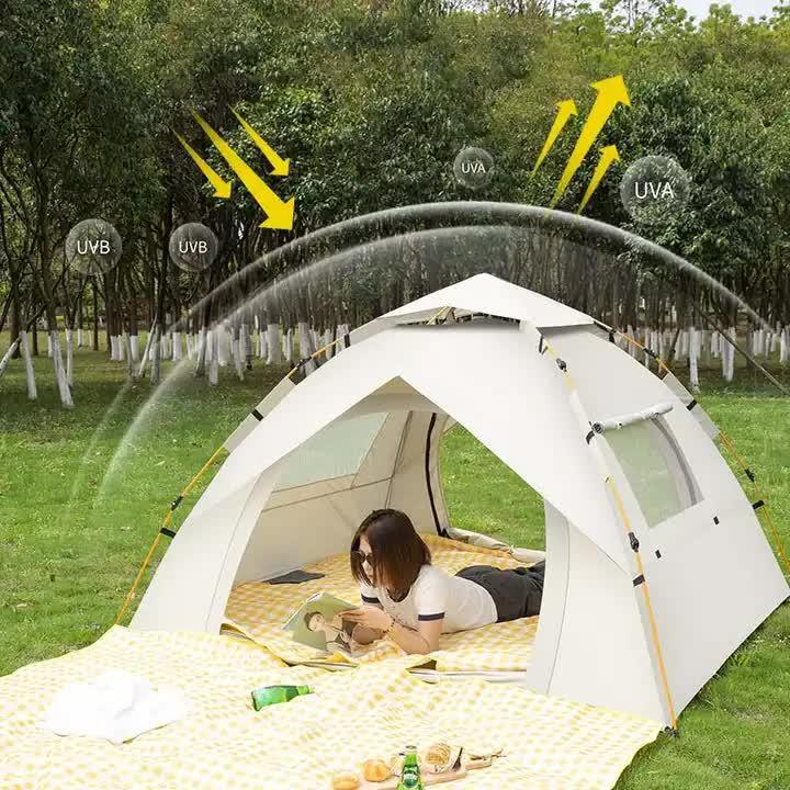 Woman reading inside white UV protection camping tent in green park with trees