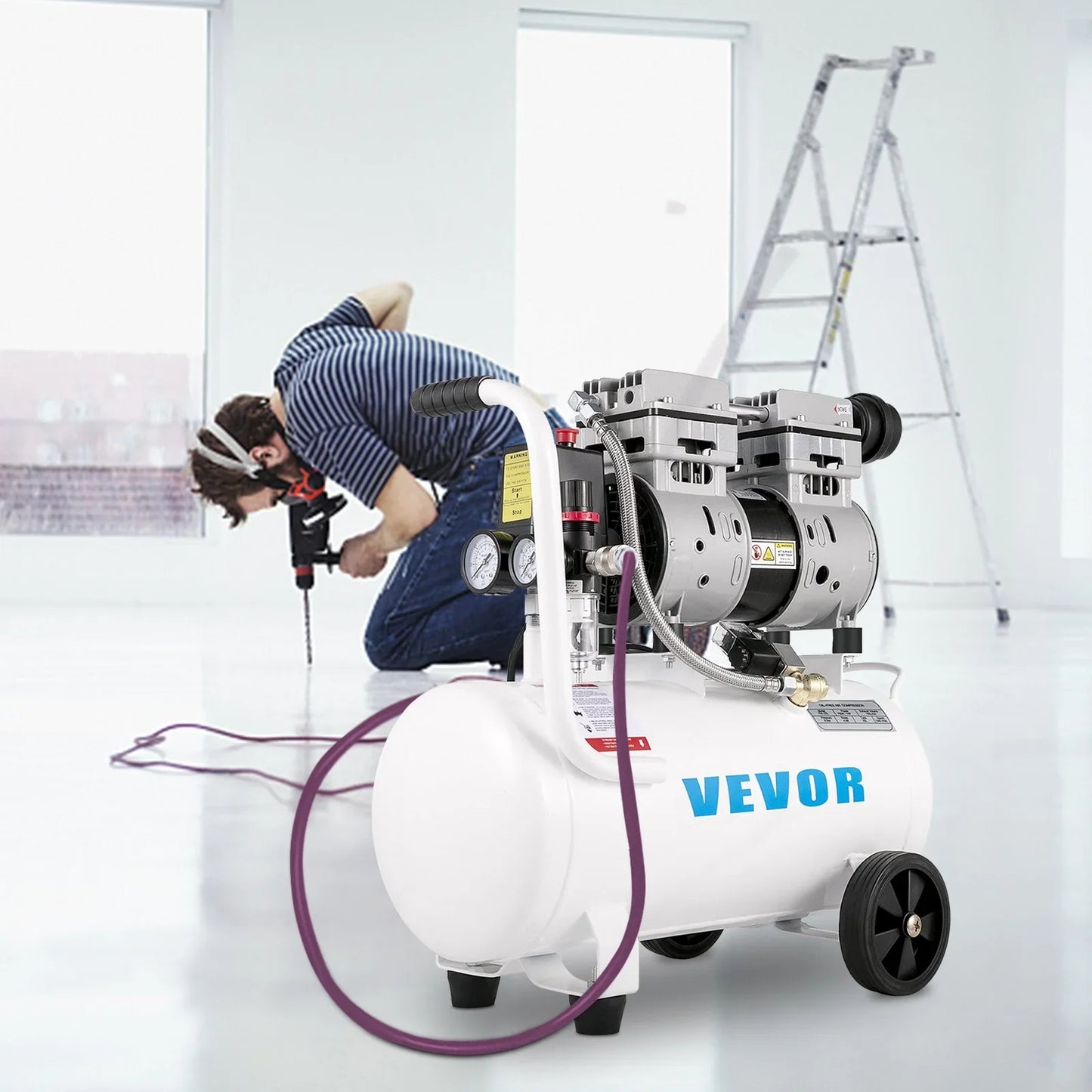 Electric air compressor with gauges and hose on floor, man using power drill, indoor setting