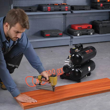 Man using air compressor and nail gun on wood panel in garage workshop