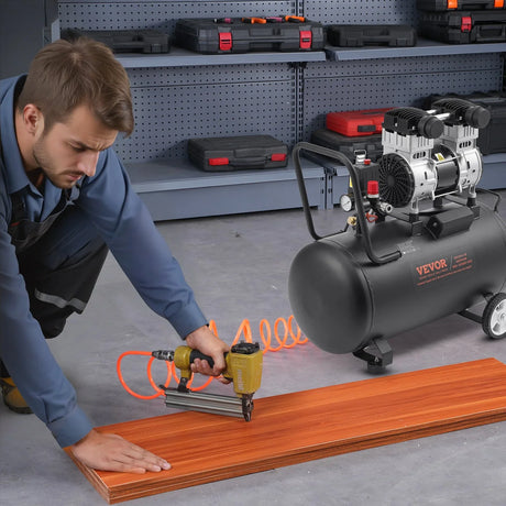 Man using air nail gun connected to Vevor air compressor on wood panel in workshop