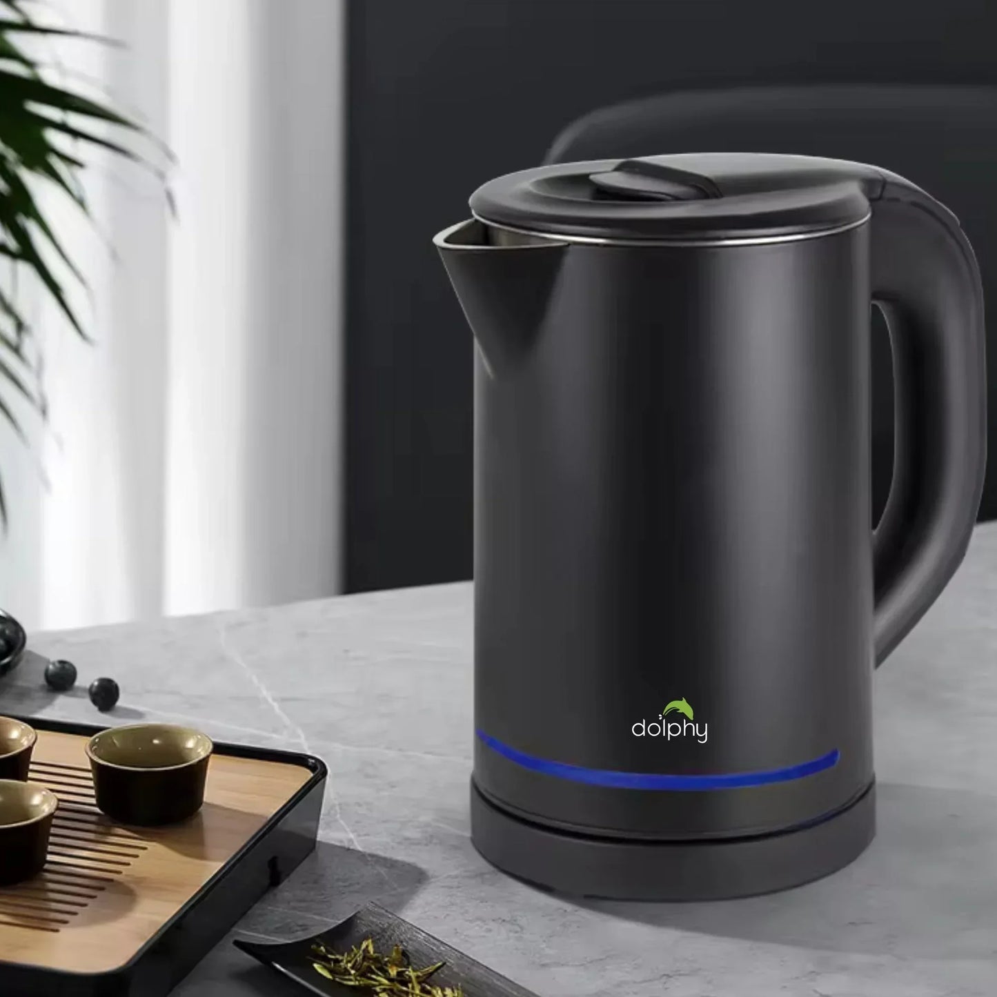 Black Dolphy electric kettle with blue light on gray countertop near tea tray and cups