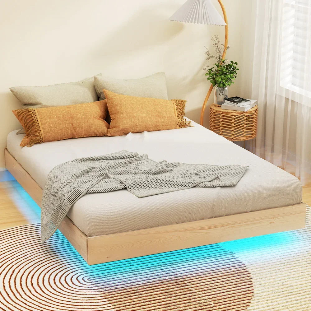 Modern wooden platform bed with beige bedding, mustard pillows, knitted throw, blue LED lights, and rattan side table